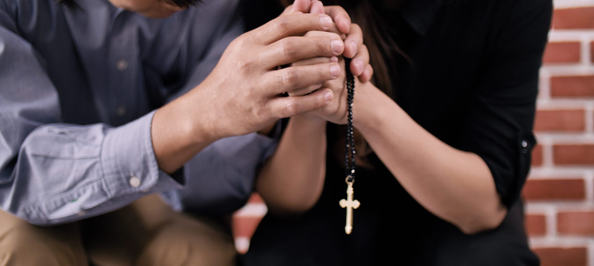 A young Asian Christian couple praying to Jesus Christ in a church.